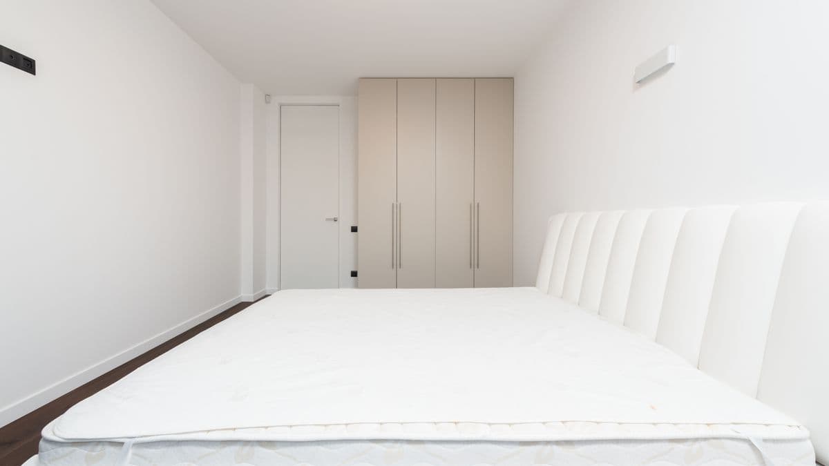 Colchão branco e limpo sobre uma cama em quarto iluminado